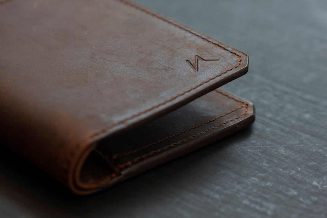 brown leather bifold wallet on gray wooden table