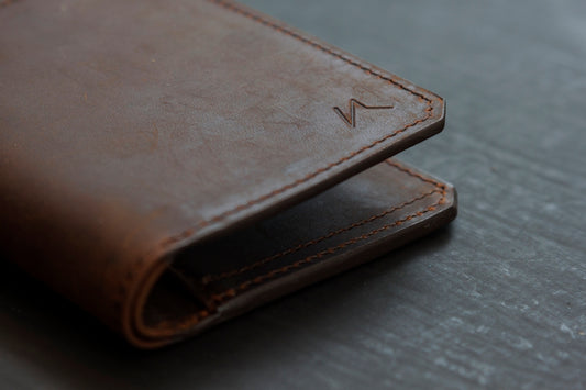 brown leather bifold wallet on gray wooden table