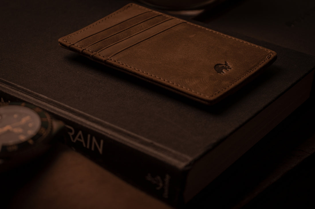 a wallet sitting on top of a book next to a watch