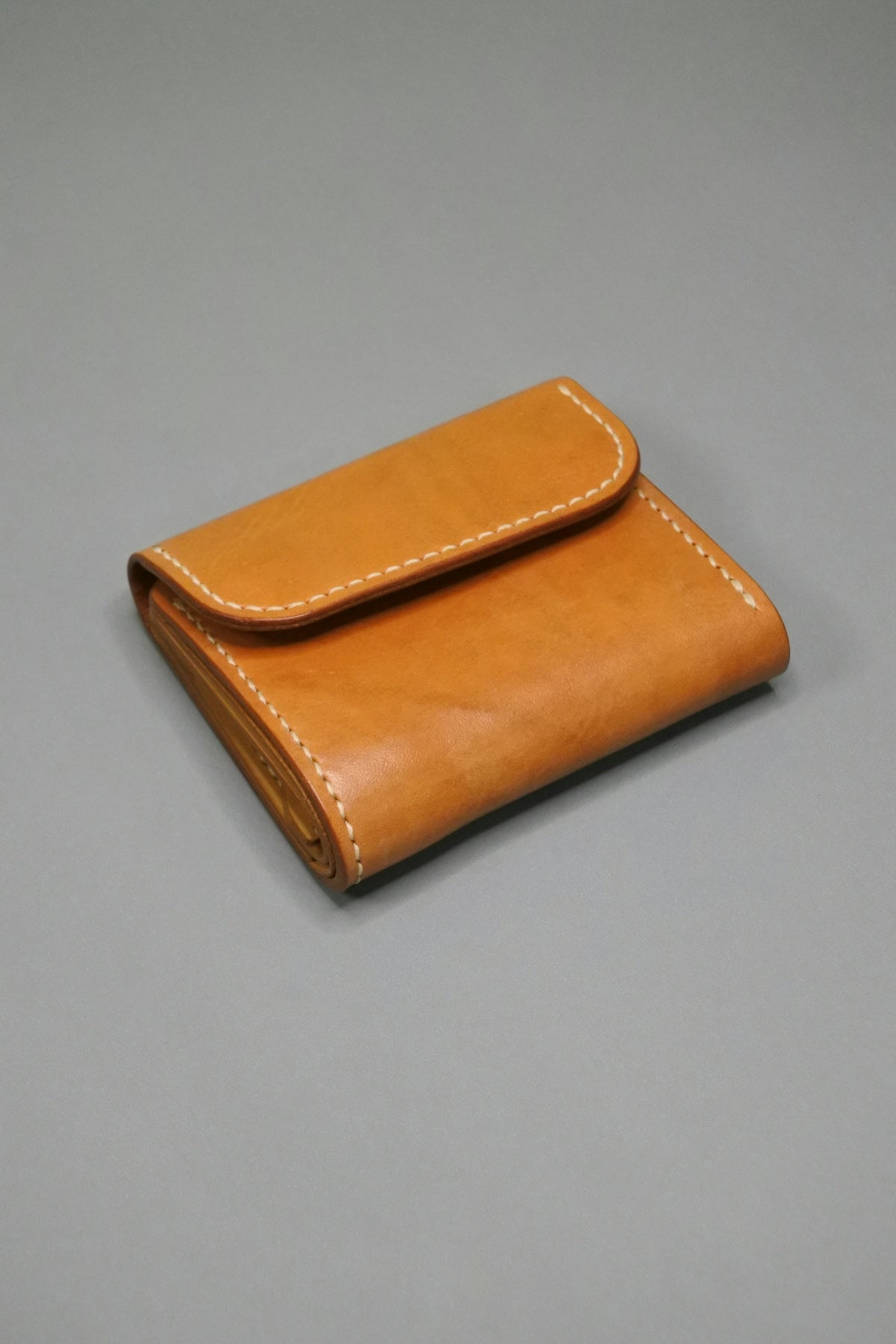 a tan leather wallet on a gray surface