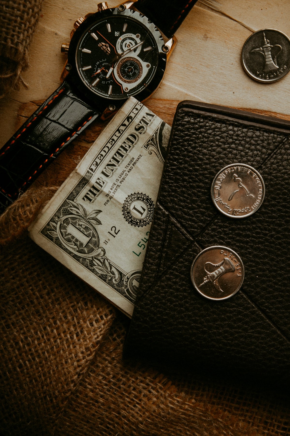 a wallet, watch, and money are on a table